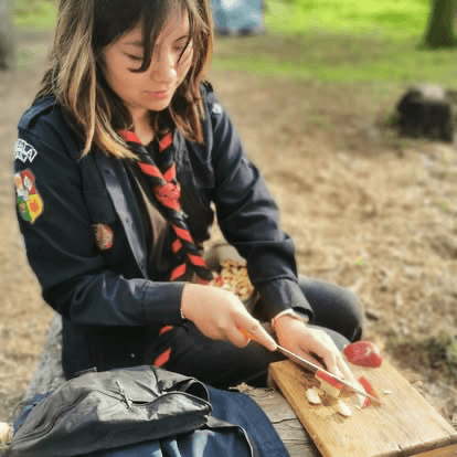 Scout aprendiendo a preparar alimentos en una actividad al aire libre